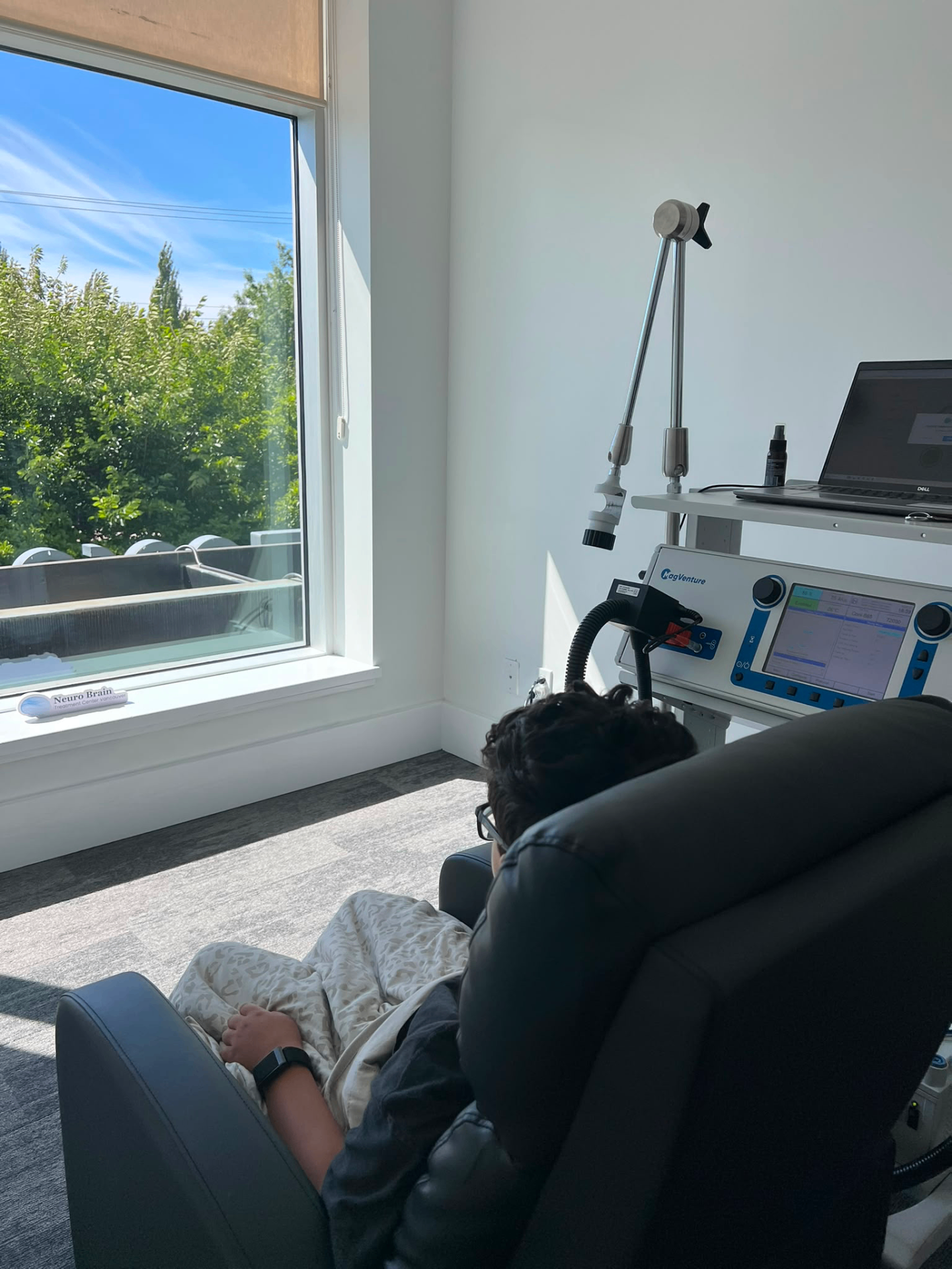 A patient resting in the MeRT® treatment chair beside sunlit windows