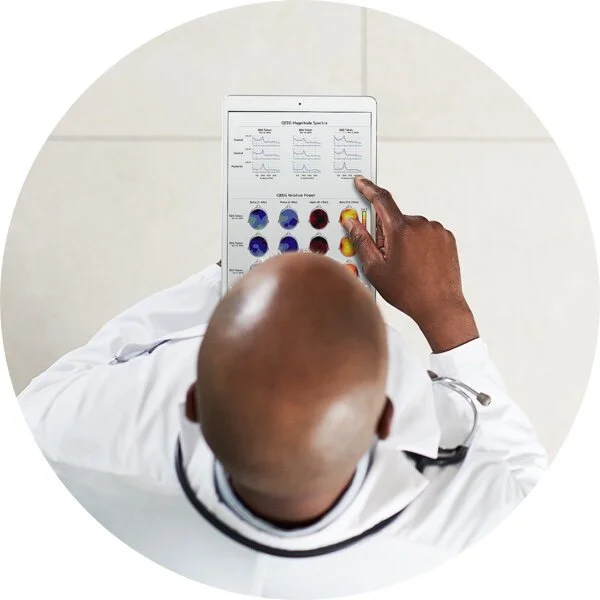 A clinician reviewing a brainwave graph on a laptop