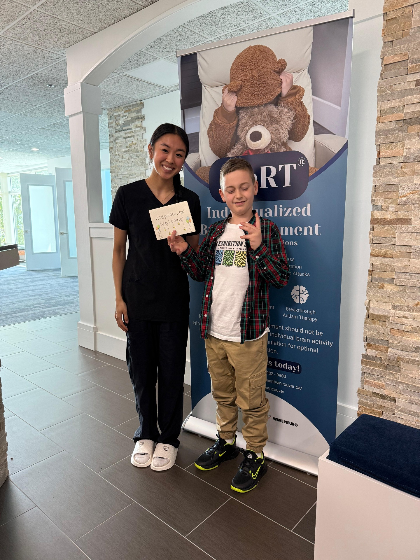A clinician welcoming a young patient in the clinic lobby