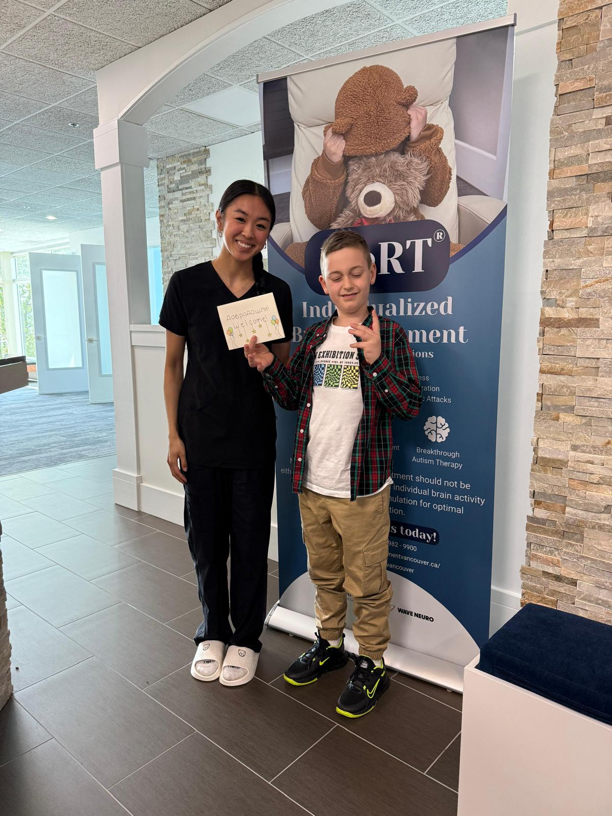 A clinician welcoming a young patient at the clinic reception