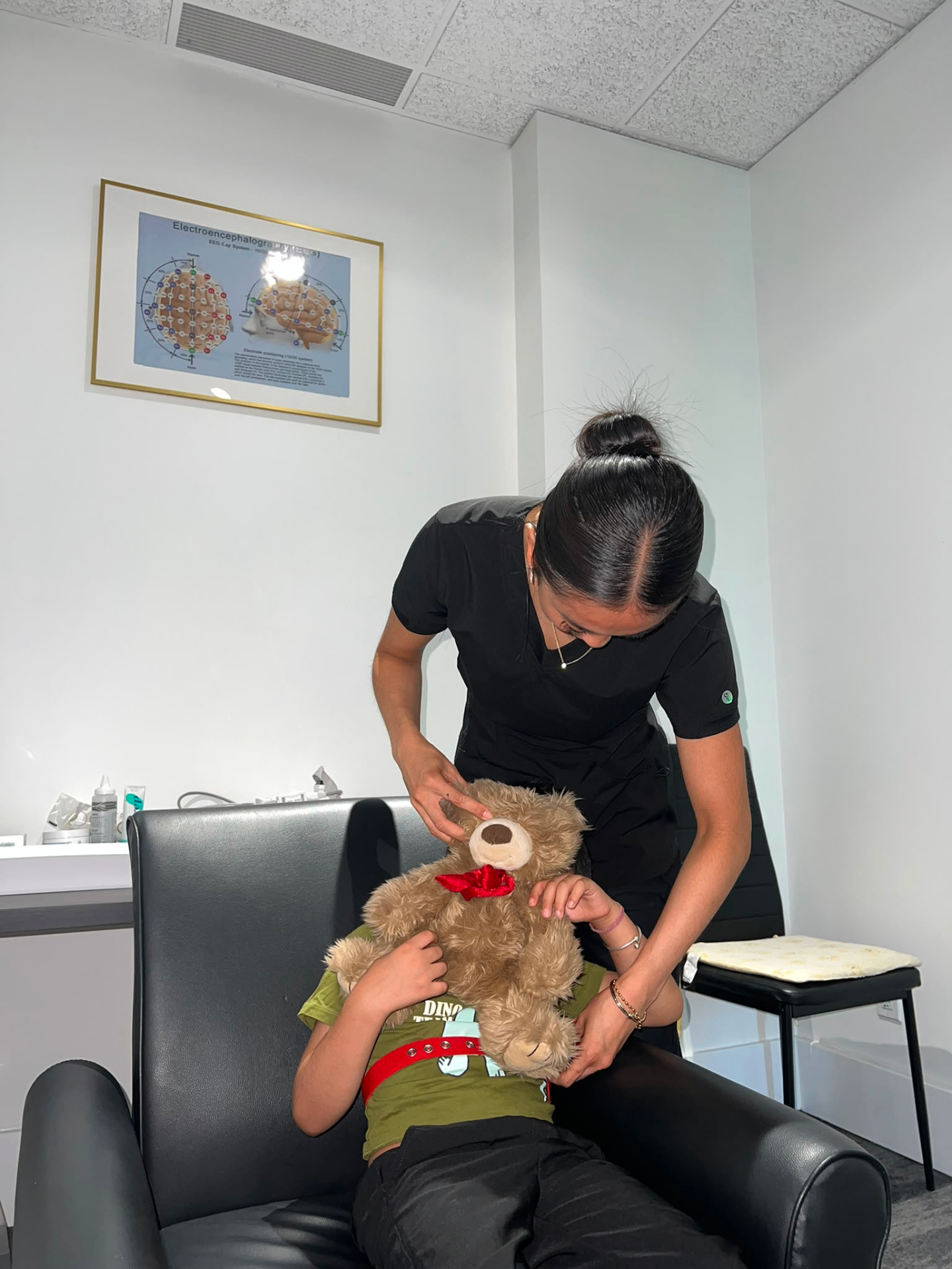 A clinician gently preparing a young patient holding a teddy bear